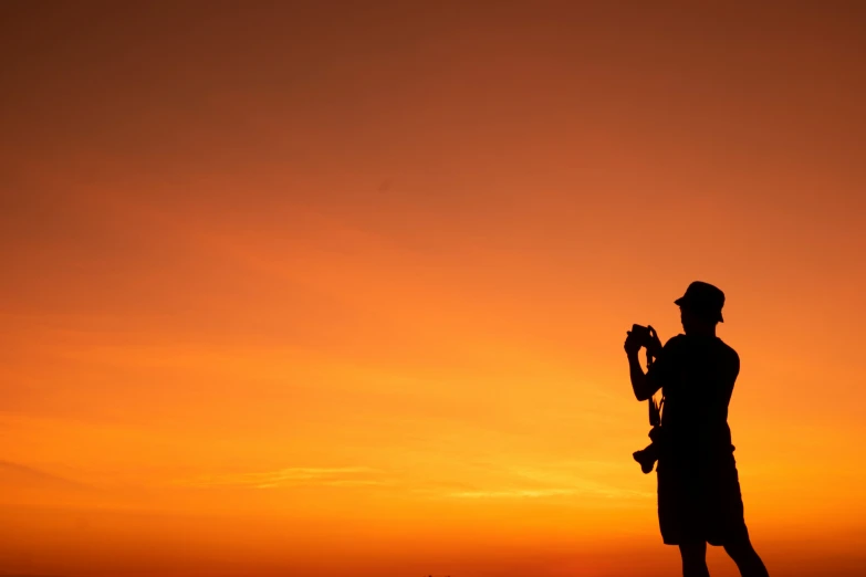 a silhouette image of a man with a parasol at sunset