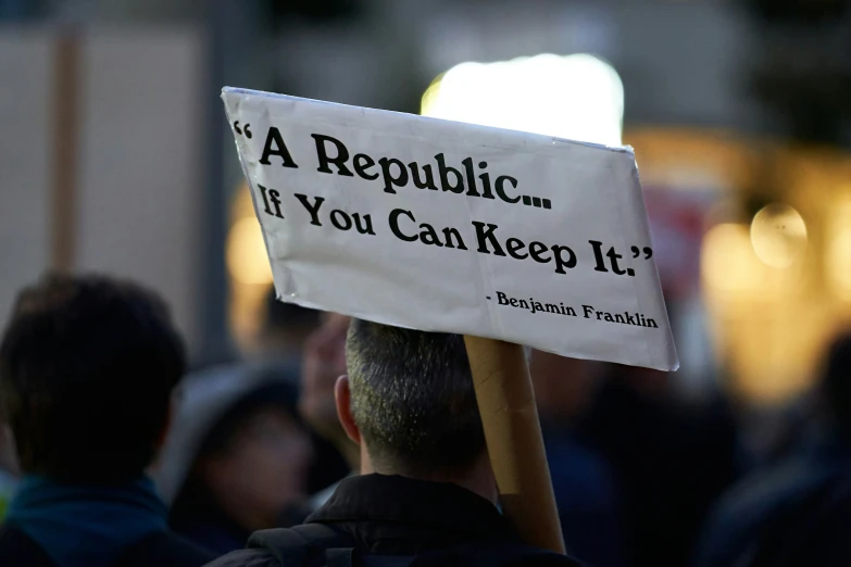 a protest rallyer holding a sign saying,'a republican isn't if you can keep it '