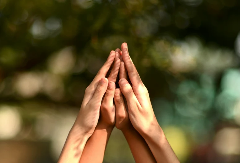 four people's hands in the air reaching for soing