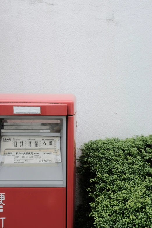 an old fashioned machine with papers on it next to shrubbery