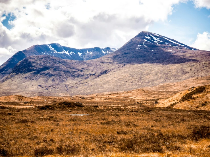 an empty field with a mountain and snow covered peaks