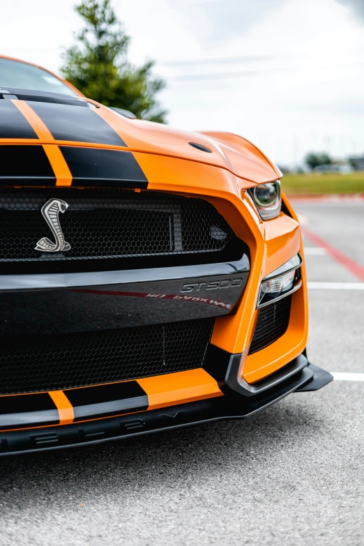 this ford mustang is orange with black stripes