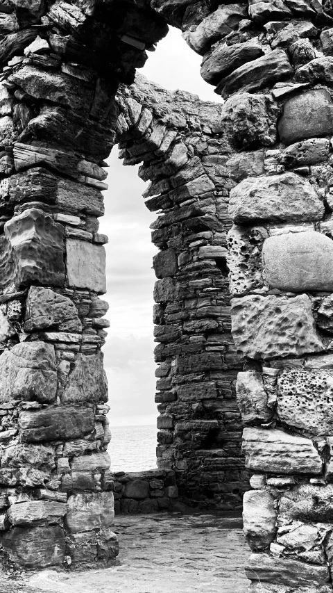 an archway into a cliff side that has water in the distance