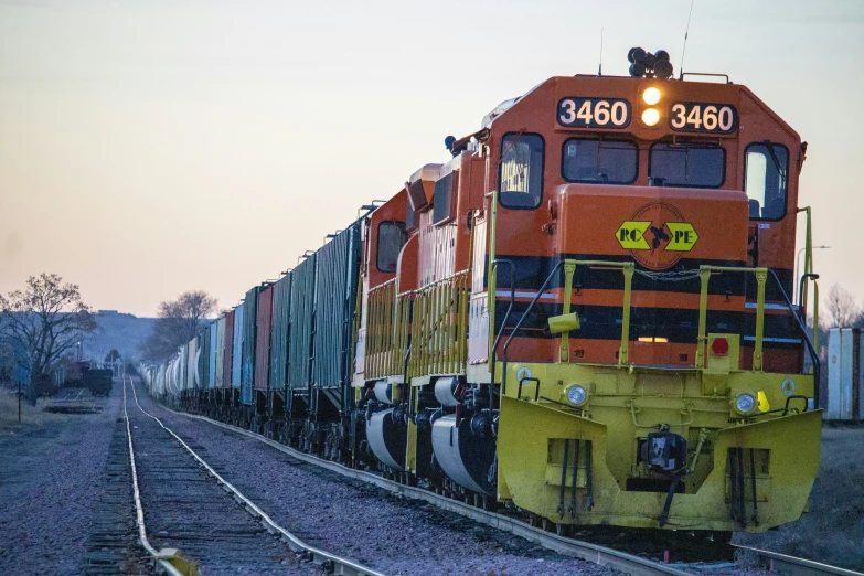 an orange train is making its way down the tracks