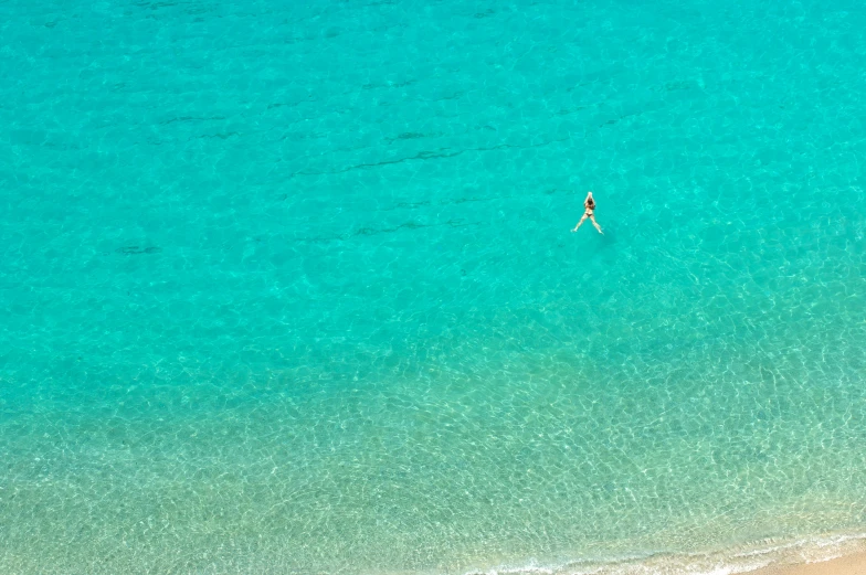 two people are swimming in clear blue ocean water