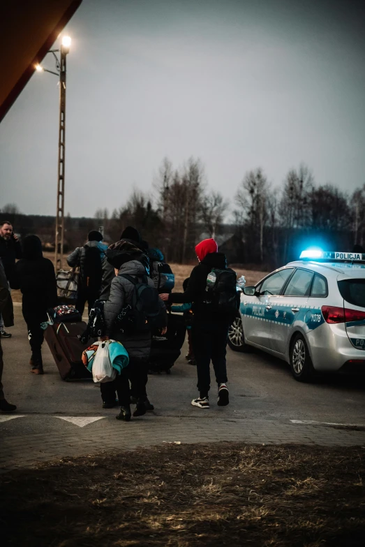 people are standing near some parked cars with their luggage