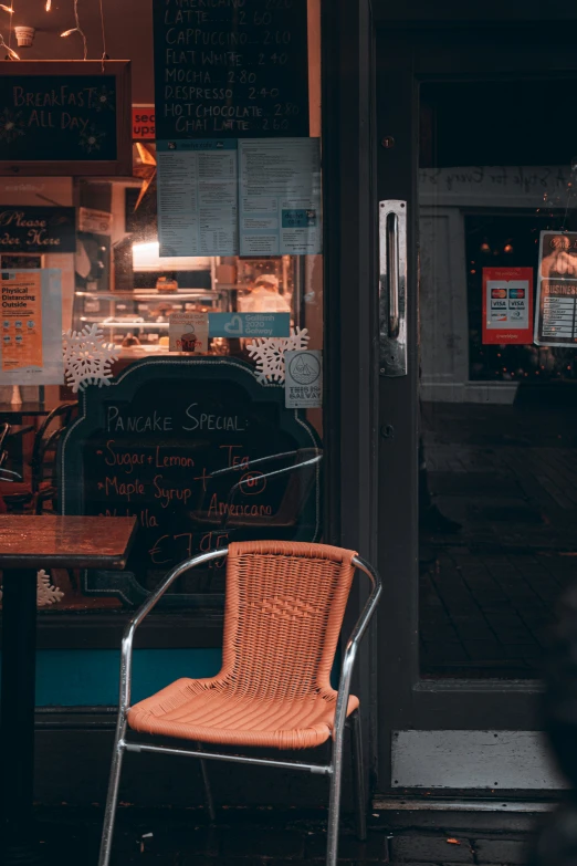 a chair outside in front of a restaurant with menus behind it