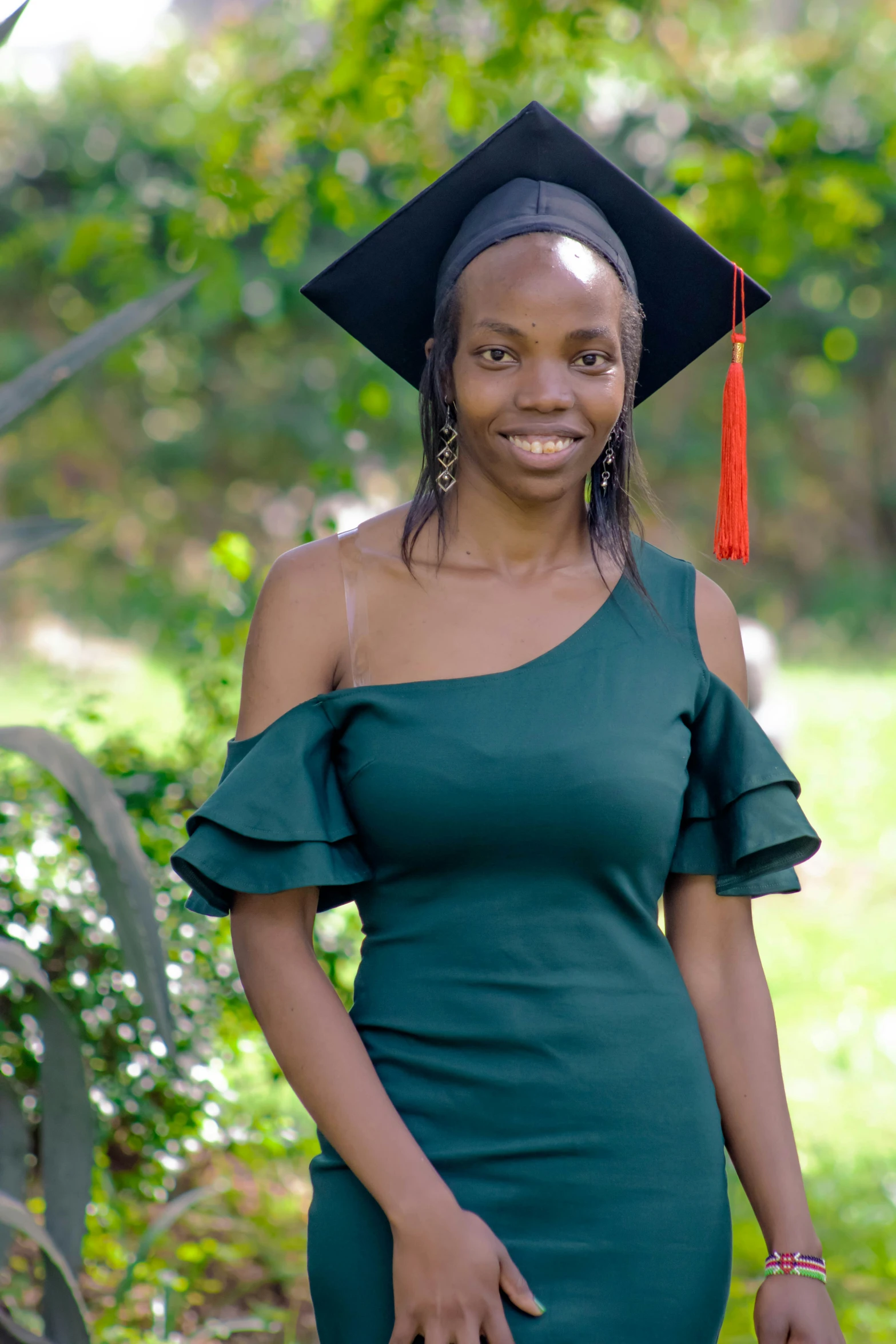 an african american female student wearing a green graduation gown