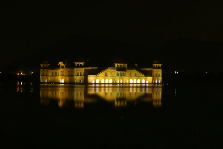 an elegant mansion is lit up at night on the water