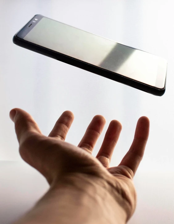 a hand reaching up towards a cell phone