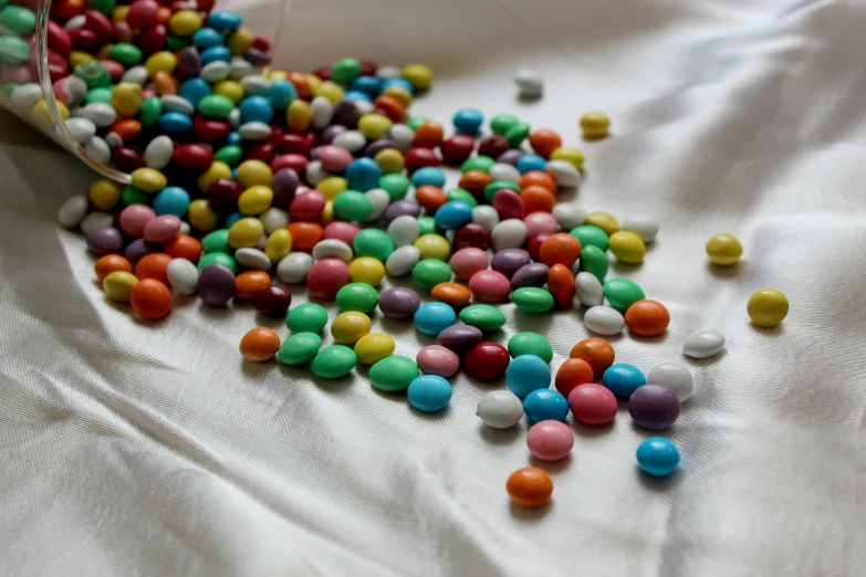 a bowl of candy sprinkles lying on top of a sheet