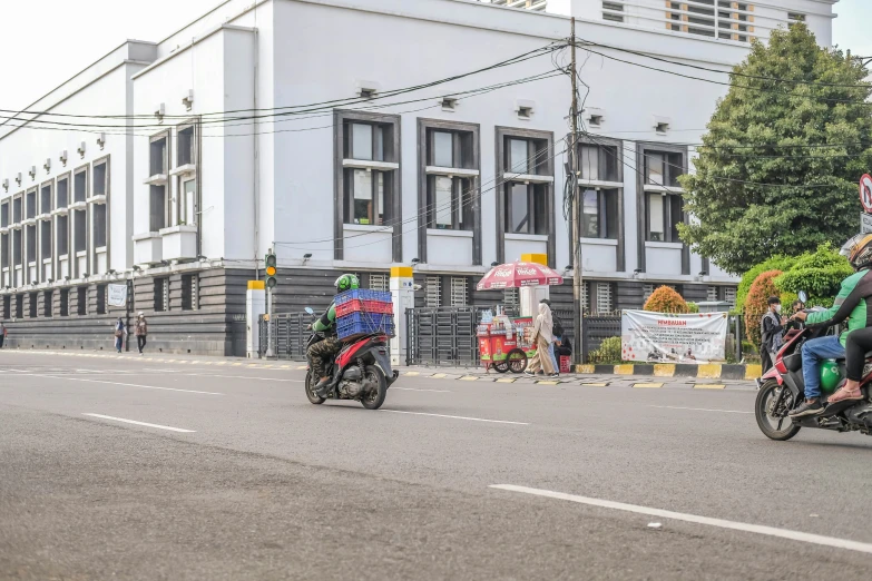 two men on motorcycles riding down a street