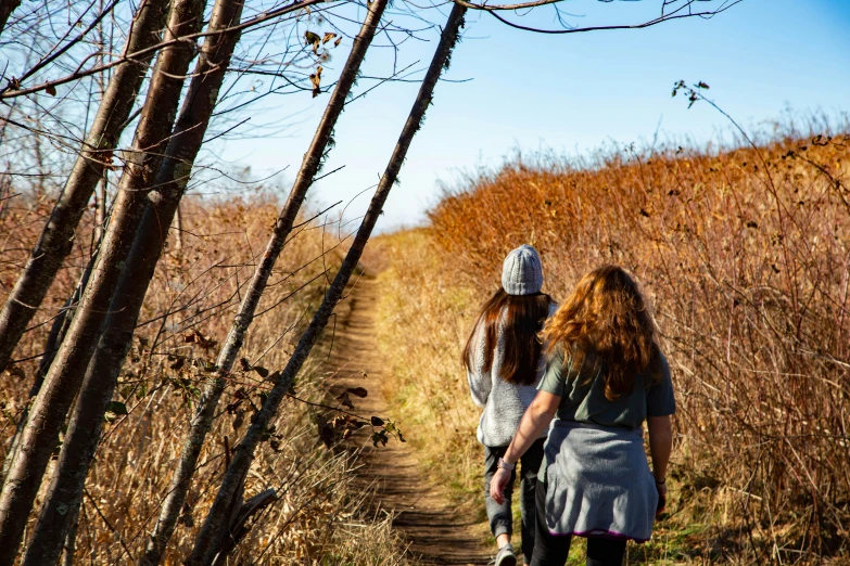 two girls walking down a path next to tall plants