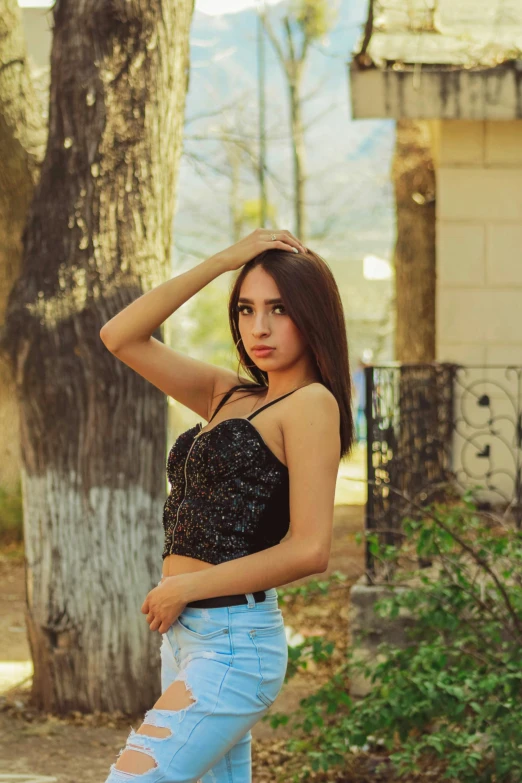 young female standing in front of a tree posing for a po