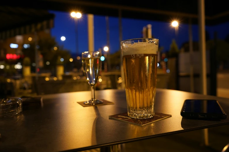 a close up of two drinks sitting on a table with lights in the background