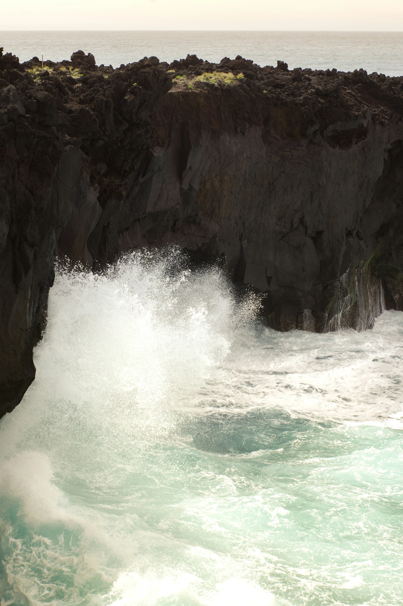 a body of water near a rocky cliff and a surfboard