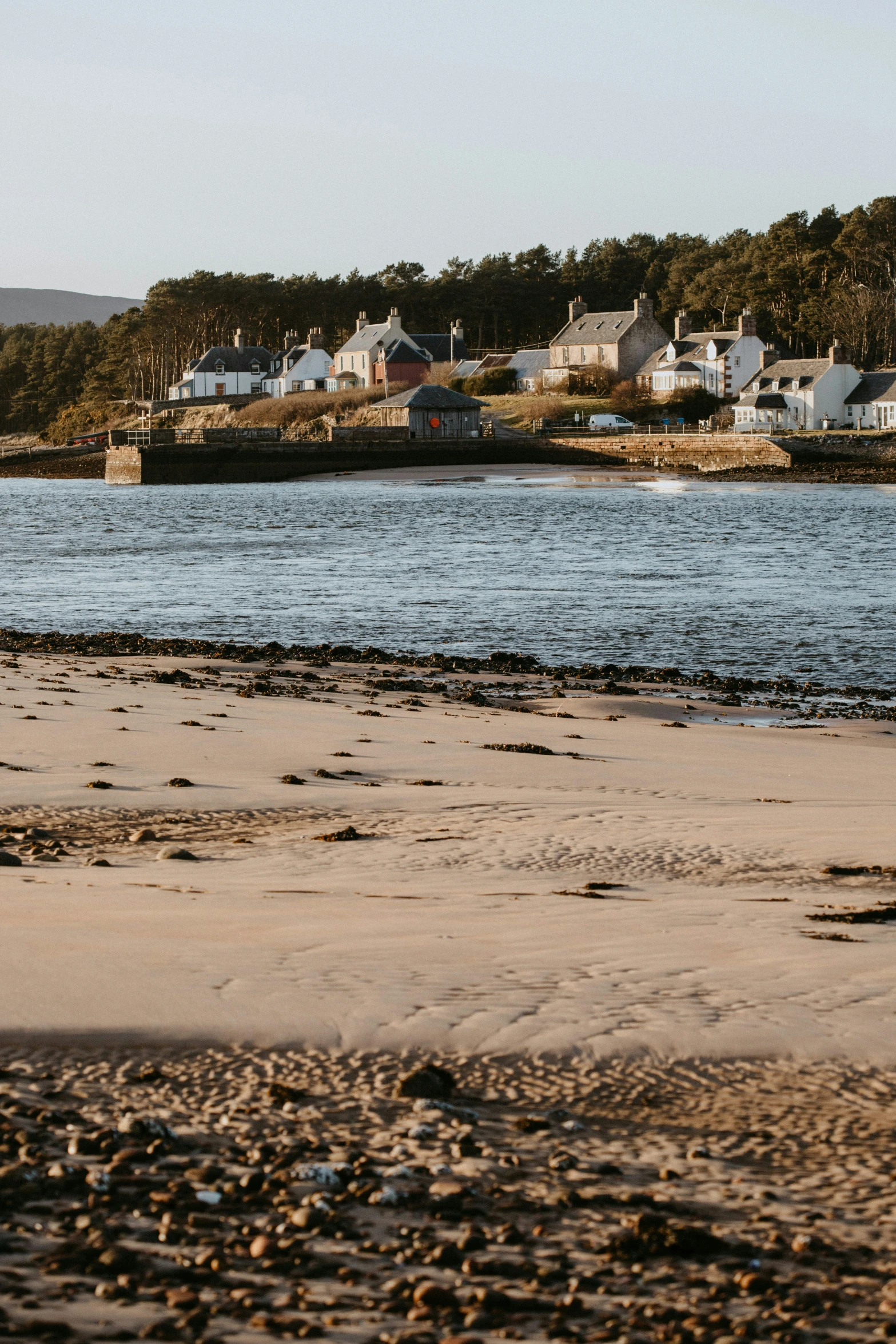 view from the shore looking across the water of a beach with lots of houses and homes