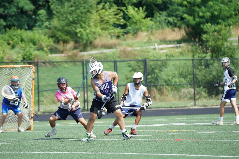 several people with lacrosse sticks and helmets playing on the field