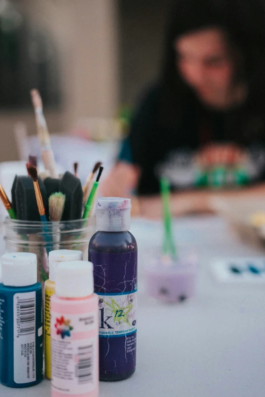 a cup full of paint, brushes and markers