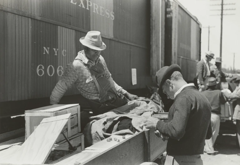 a black and white po shows men loading belongings onto a train car