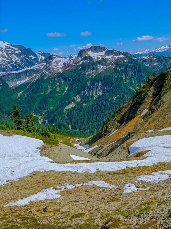 snowy, patchy hills near some mountains