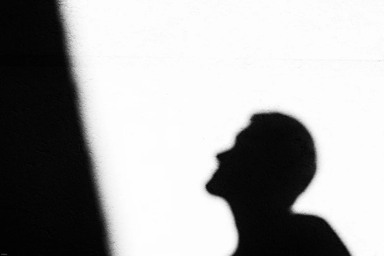 a person looking up in the shadows of a white wall