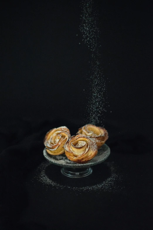powder sprinkled over two small pastries in a glass dish