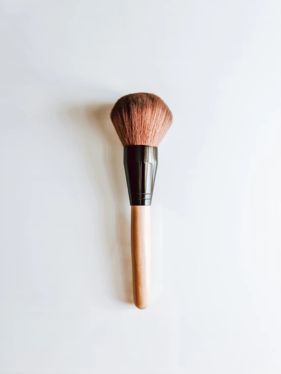 the bare makeup brush is laying on top of the white wall