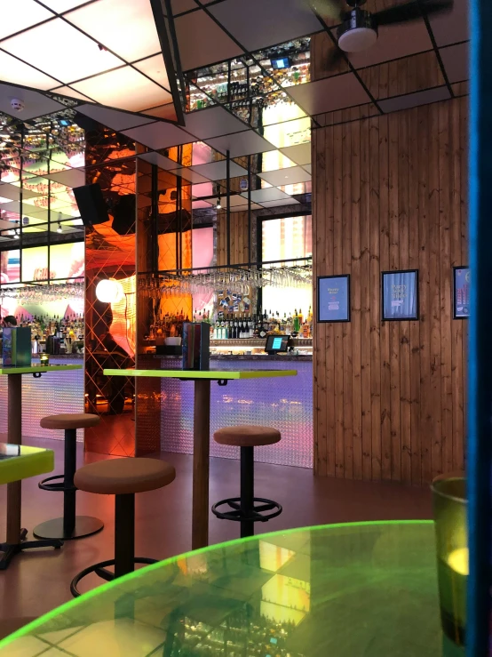 a bright, illuminated bar with stools and a circular green table