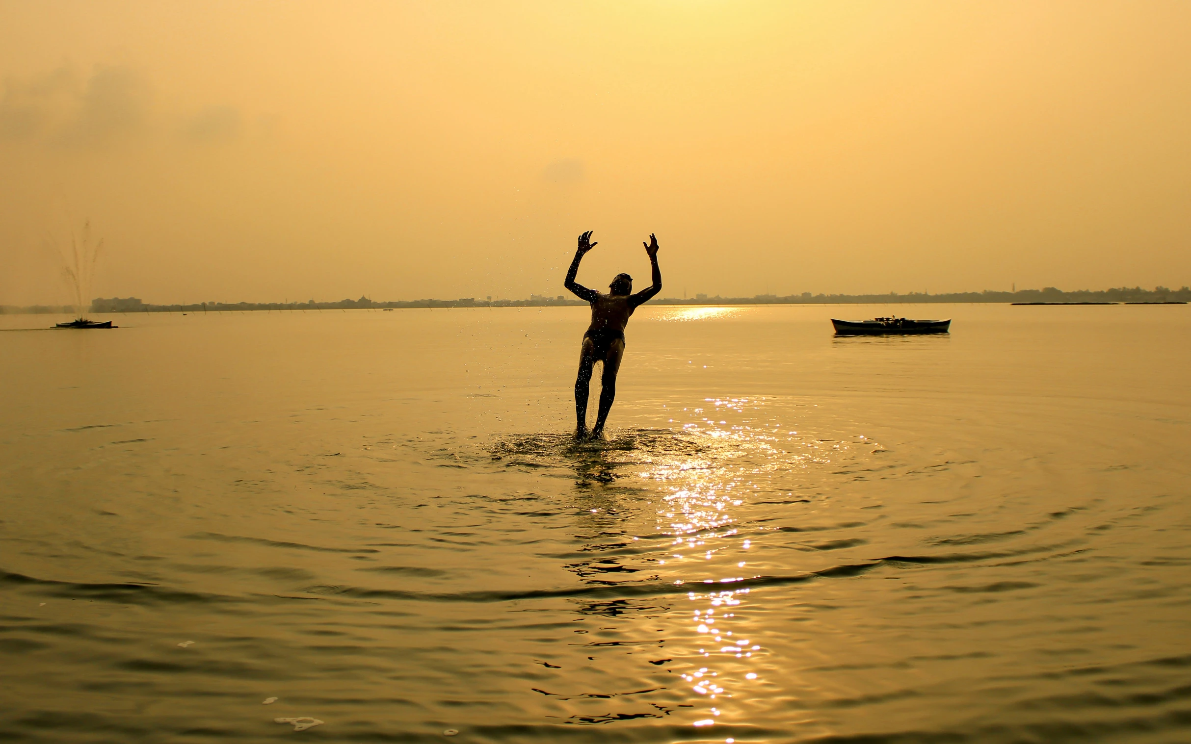 a person in the middle of a body of water, while holding two swords