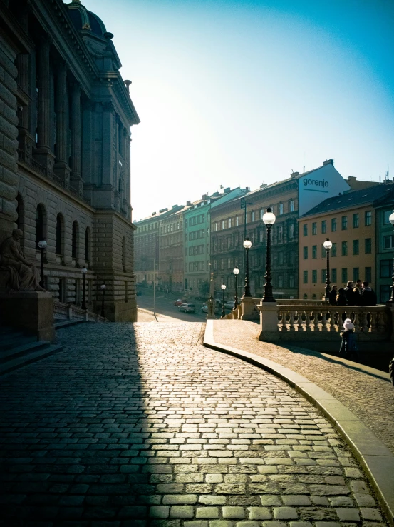 the street with cobblestones is lit by lamps