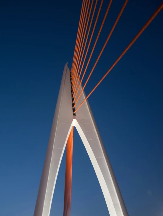 a very tall red and white bridge with an orange and white flag