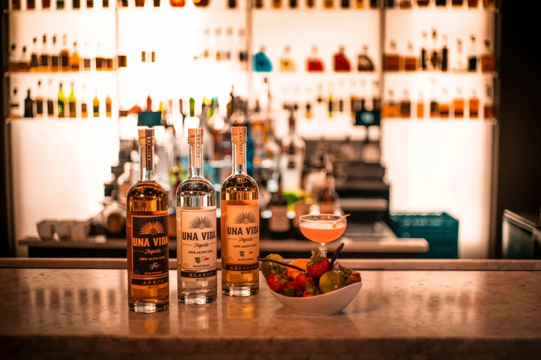 the bottles of booze are sitting on the counter next to two glasses