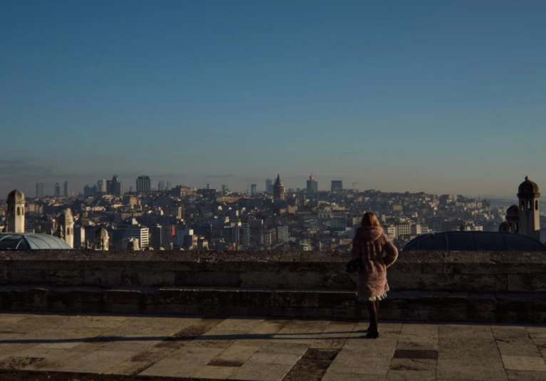 a woman standing on a ledge looking over the city