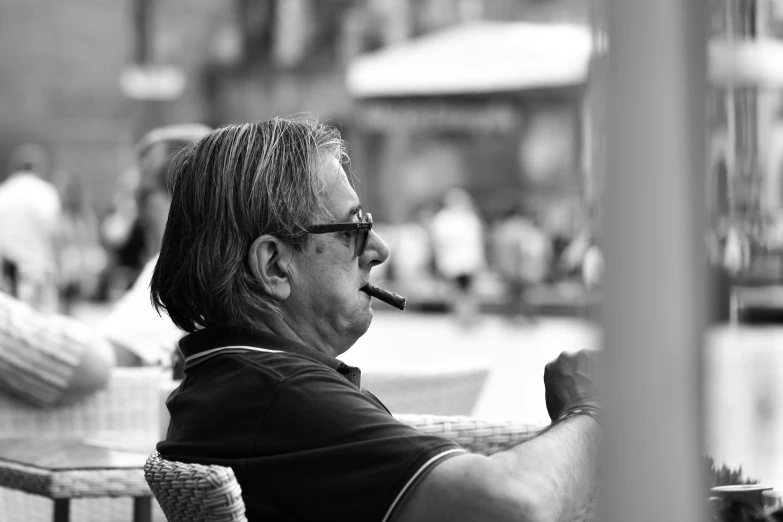 a man smoking a cigarette sitting at a table in a cafe