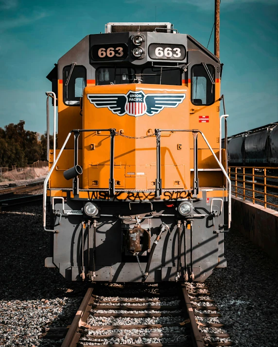 a yellow train traveling past another train station