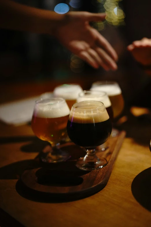 several glasses of dark ale sit on a bar