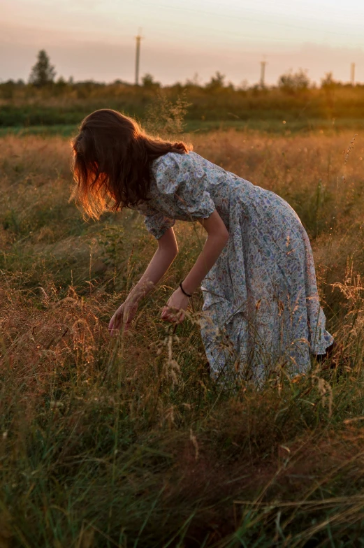 a woman is bending over in a field of grass