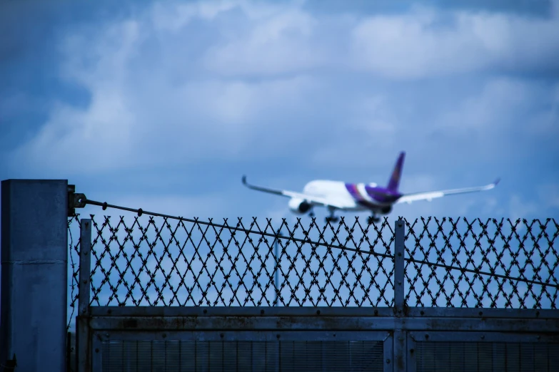 a plane taking off into the sky over a fence