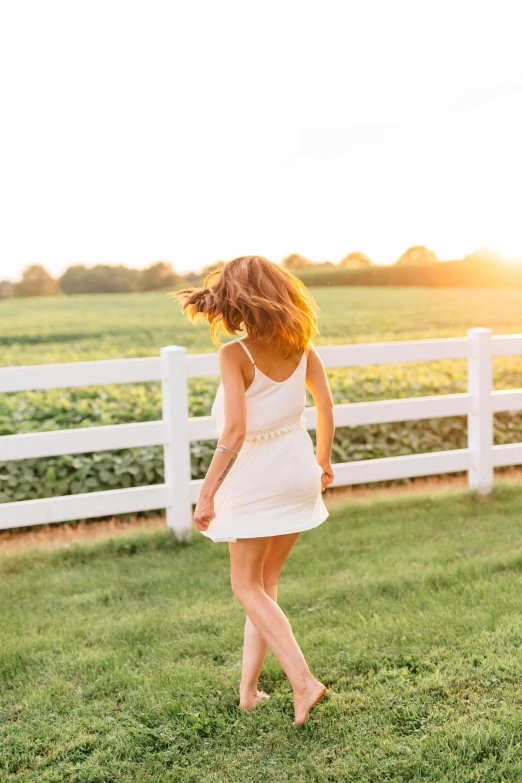 a woman in white dress walking across grass