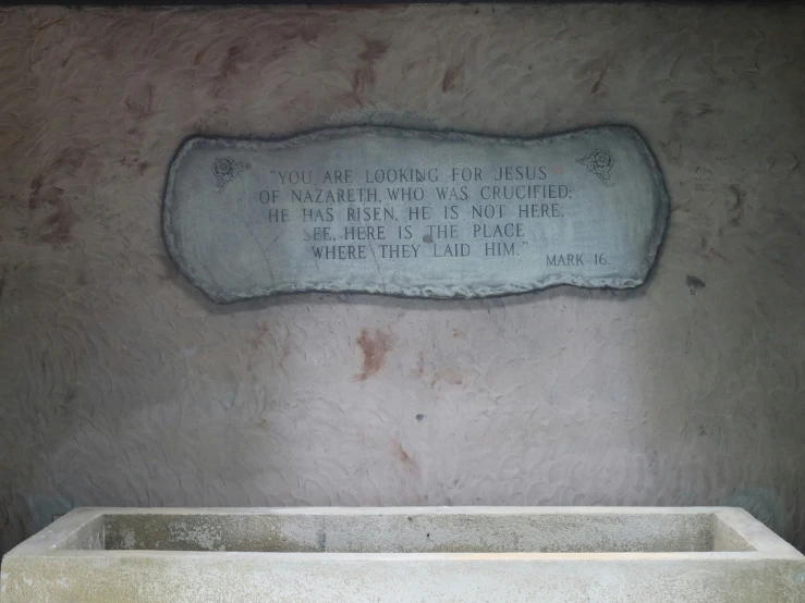 a concrete bench in a bathroom with a plaque on the wall