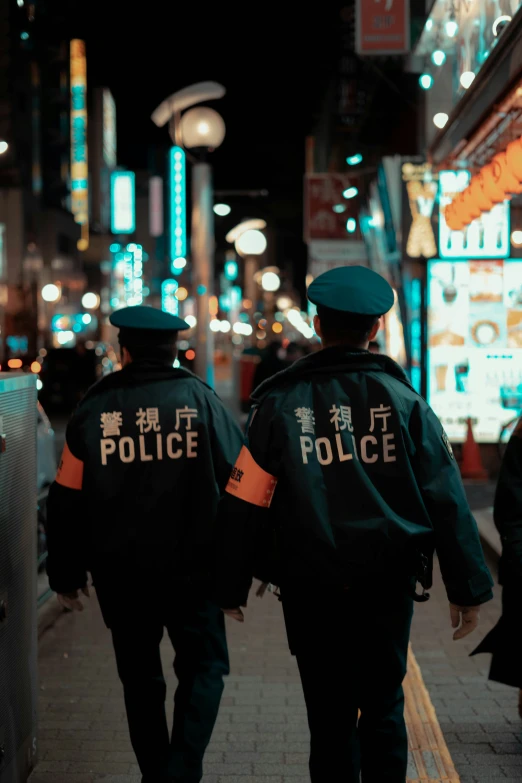 two policemen walk on a busy street at night