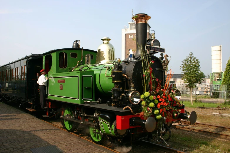 a person standing in the train beside a green locomotive