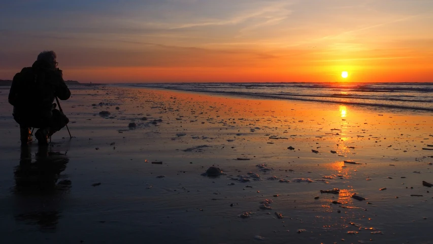 a person on a beach walking with the sun in the background