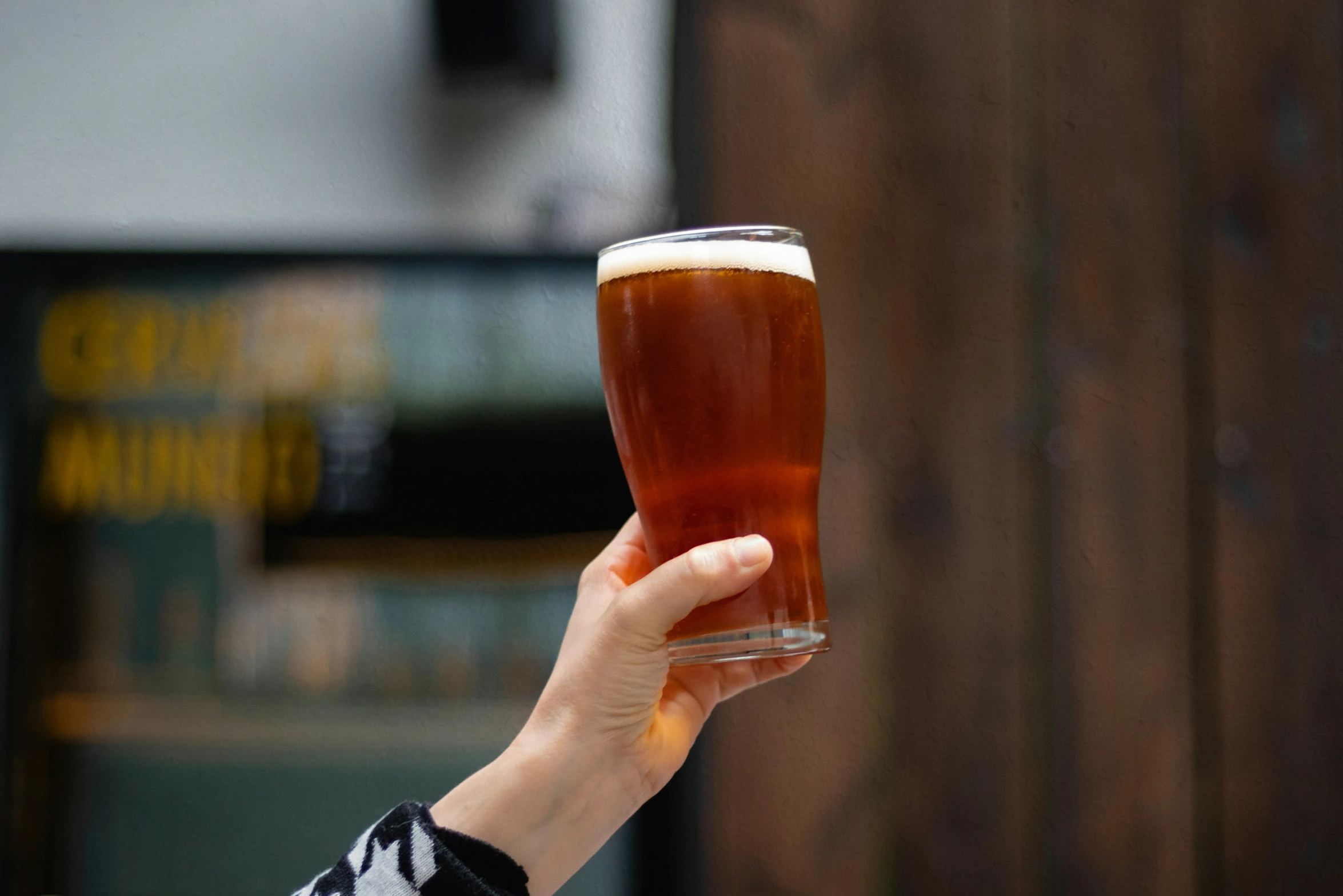 a hand holds a glass with a beverage