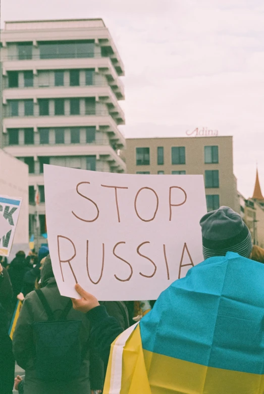 a person holding up a sign reading stop russia