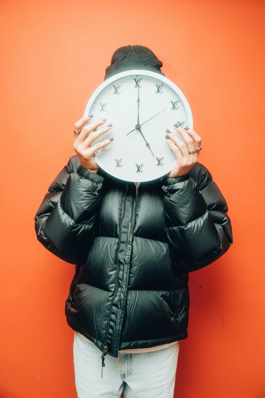 woman covering face with clock on red background