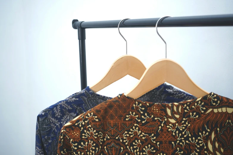 two shirt hangers on top of clothes on a rail