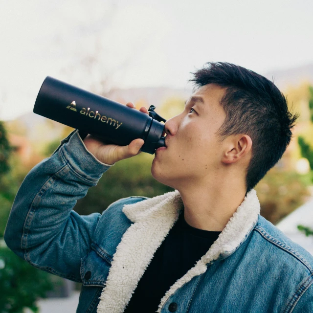 a man is drinking from a black cup