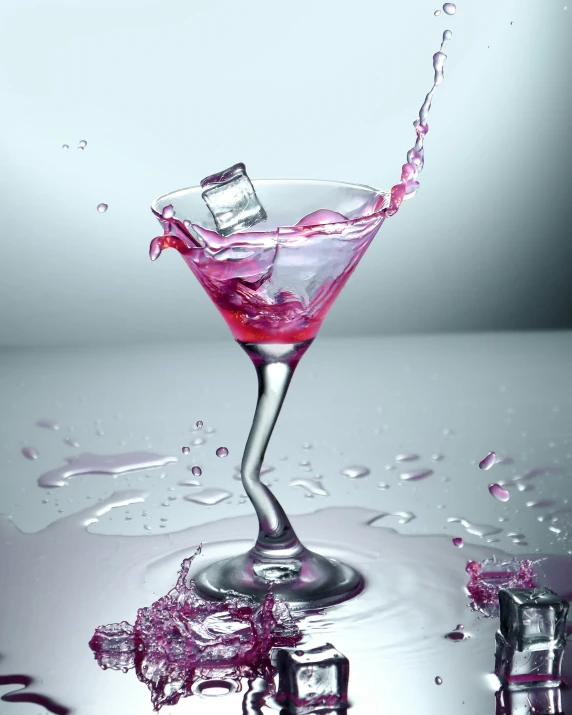 a martini drink with ice cubes and a pink liquid